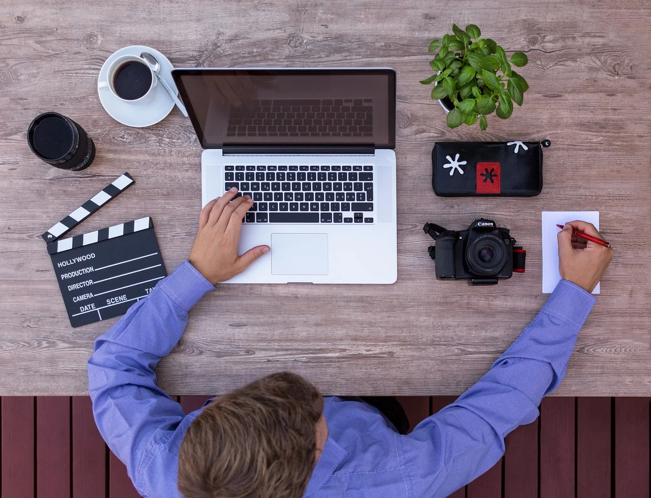 Overhead view of a creative workspace with a storyboard, camera, and laptop
